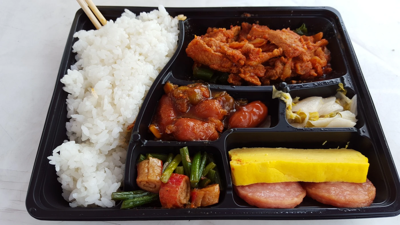 Opened Korean convenience-store dosirak with rice and assorted side dishes in a compartment tray
