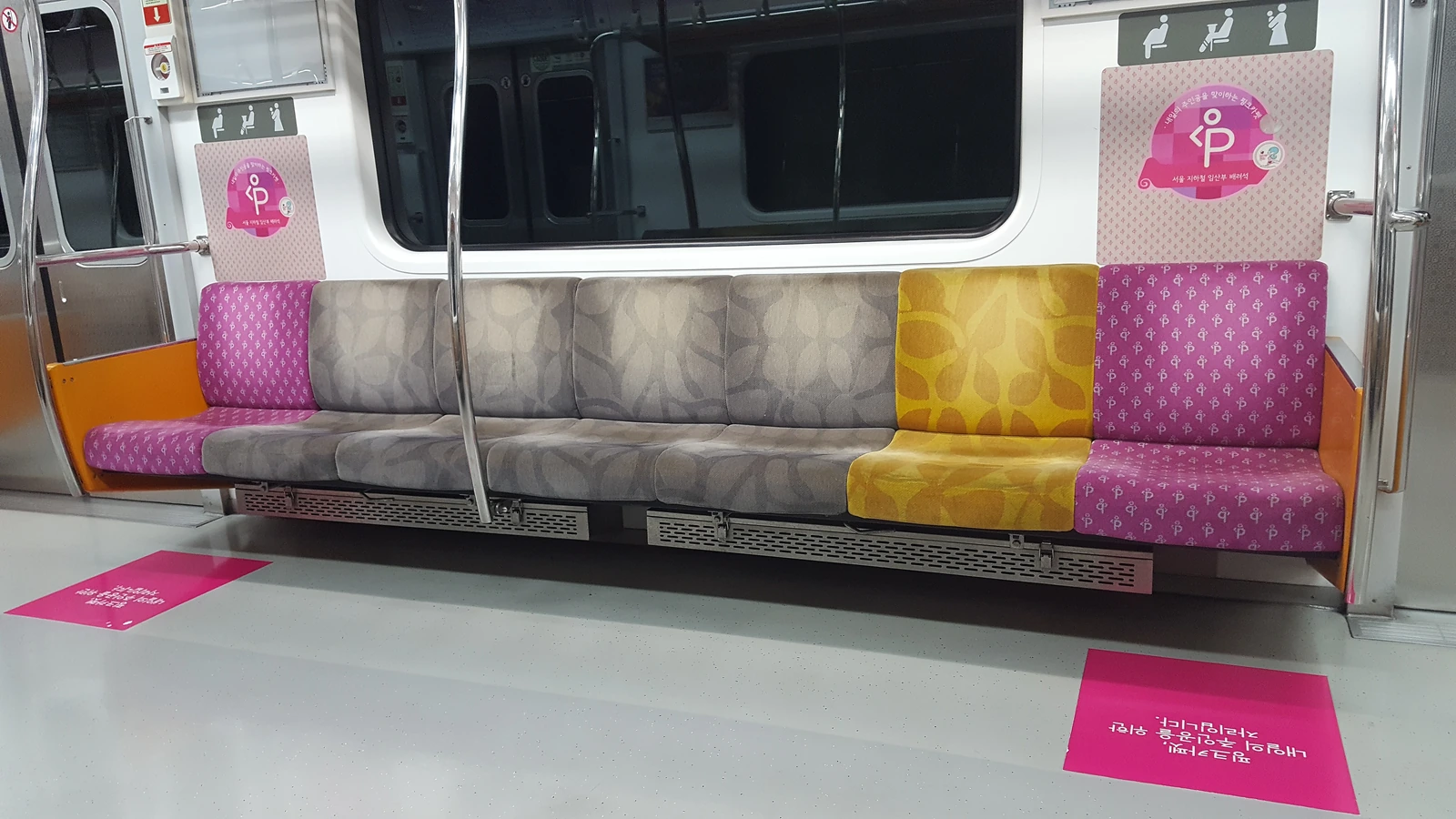 Pink marked pregnant women seating inside a Seoul subway car with empty seats and floor signs